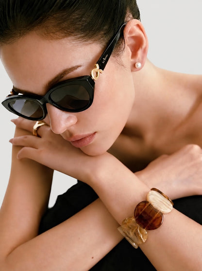 Close portrait of a model wearing Mira Black sunglasses on a light gray background.