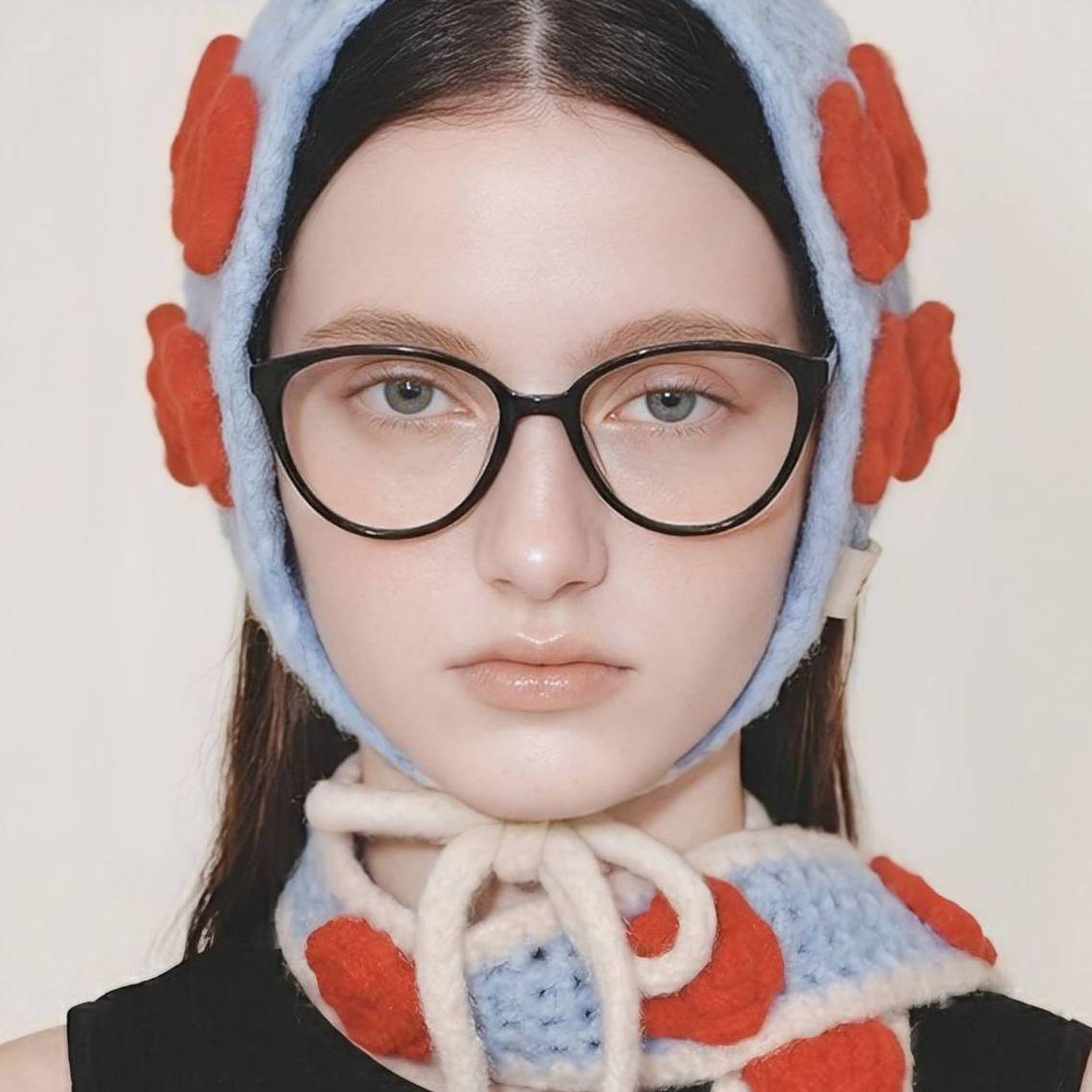 Model wearing Sienna Black cat-eye glasses in a blue knit hat, close editorial portrait