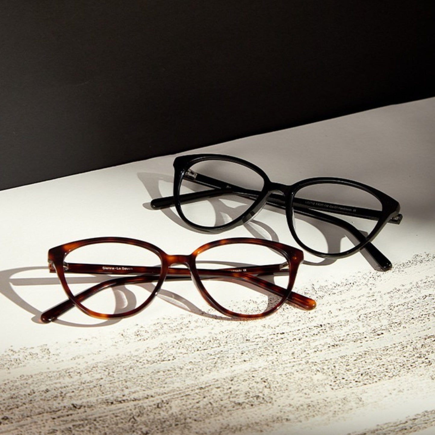 Sienna Black and Brown Tortoise cat-eye glasses on a textured editorial surface